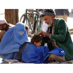  A Mother Watches as Her Child Gets a Haircut in the Center 