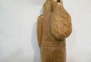 Fortin wooden carving, old man in coat and hat carrying back sack.