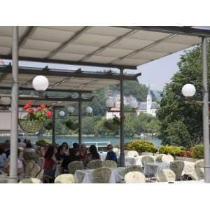 People Dining at Restaurant by Lake in Summer with St. Martins Roman 